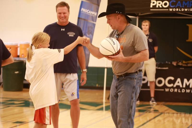 Country music superstar Garth Brooks, in his black hat, and his old college buddy, University of Kansas head basketball coach Bill Self, share a moment with a young camper Saturday at the ProCamps baskebaball camp at Elk Grove High School.